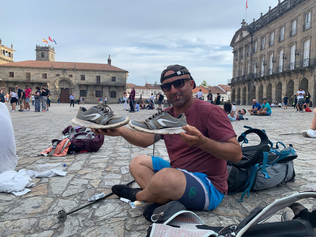 Pellegrino mostra le scarpe da running consumate arrivato a Santiago