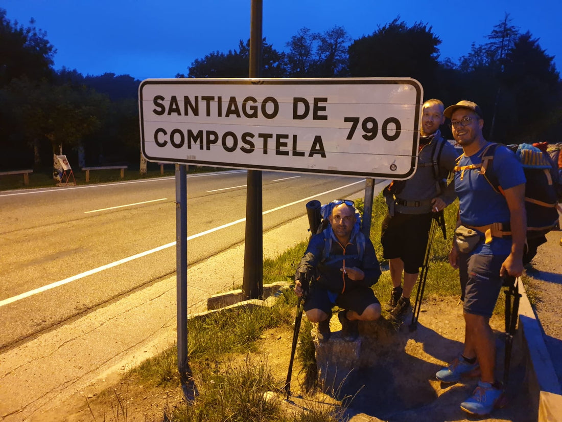 Pellegrini accanto al cartello Santiago de Compostela 790 km all'alba