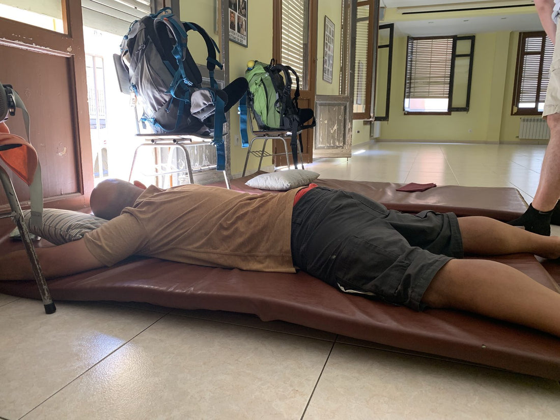 Un pellegrino dorme su un materasso appoggiato per terra nella sala di un albergue del Cammino di Santiago